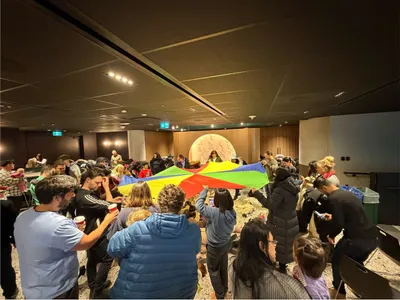Karla playing with a parachute with a group of children and their families at a birthday circle time