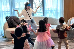 Karla, wearing a blue crown, dances and plays with children at a themed birthday party.